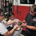 Genete, along with youth Regina & Liesel, show a fireman how to administer O2.